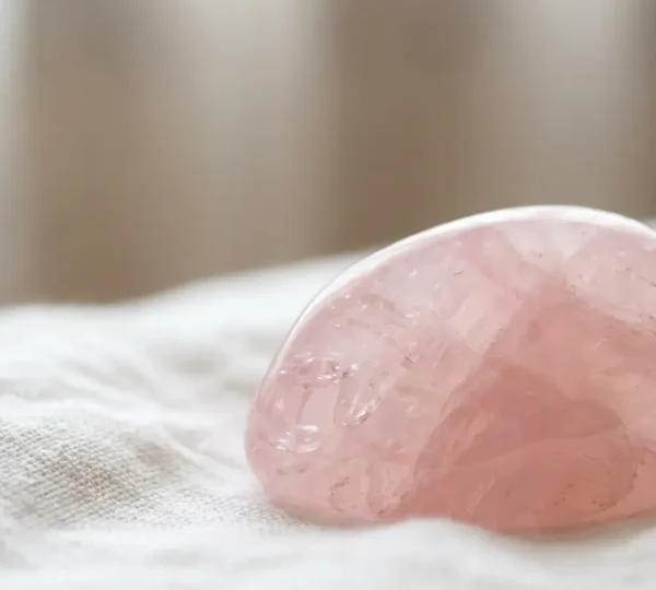 Cristallo di quarzo rosa lucido su tessuto morbido con luce soffusa che simboleggia la guarigione emotiva dopo una rottura sentimentale